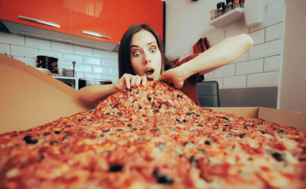 a woman attempting to eat an oversized pizza