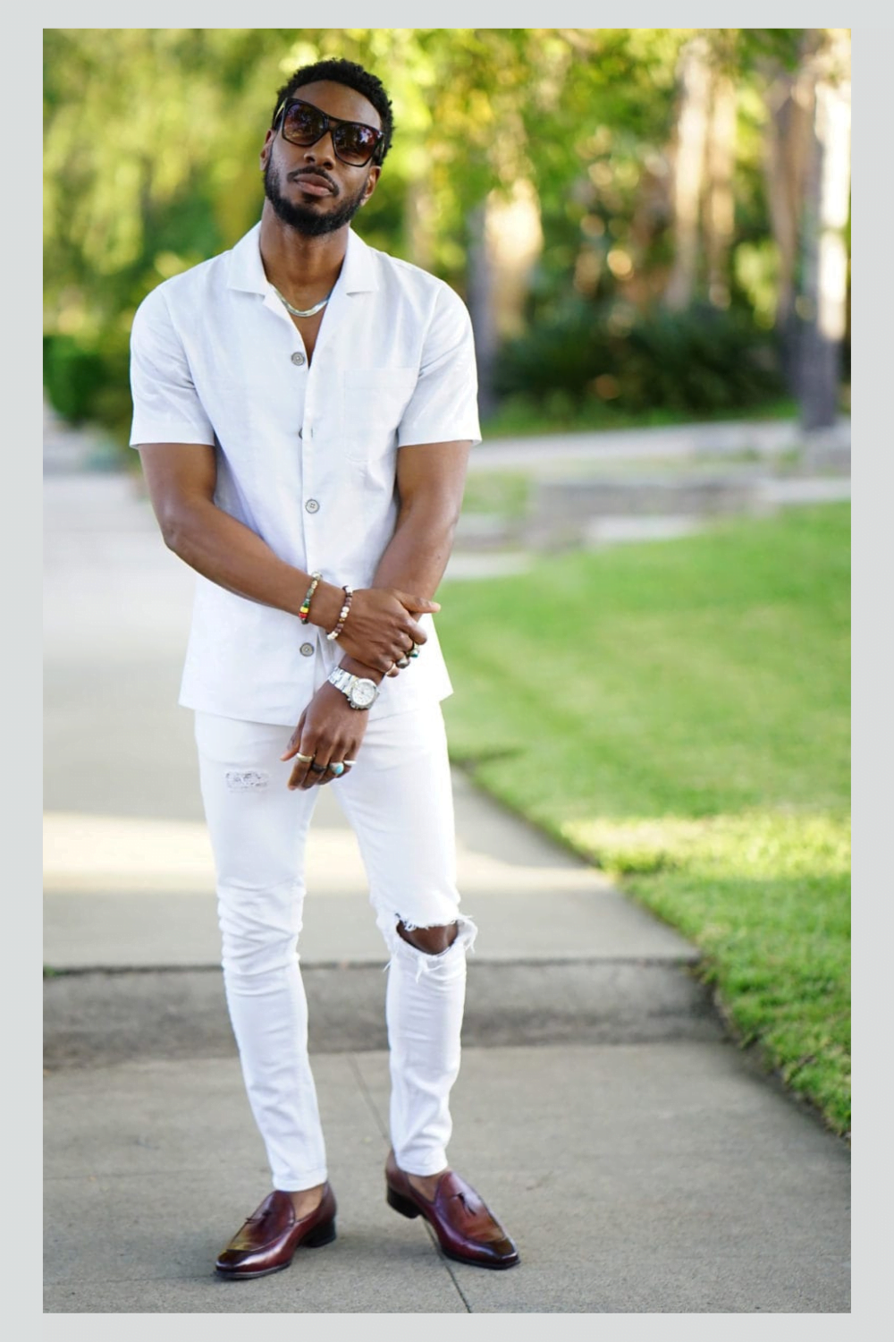 man standing outside modeling all white ripped jeans.  