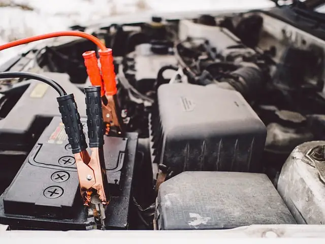 close up of jumper cables connected to the battery. red cable to positive and black connected to negative. how to jumpstart a car