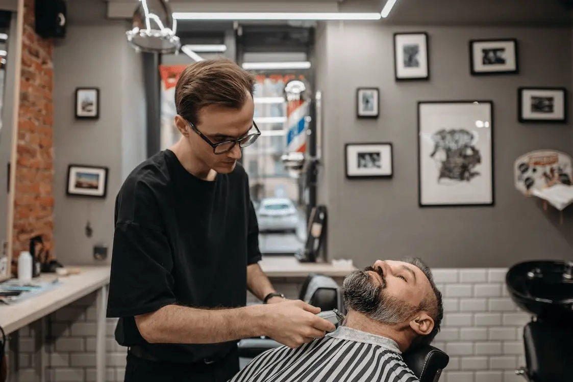 barber in barber shop using clipper to trim a mans neck line for his beard how to trim a beard