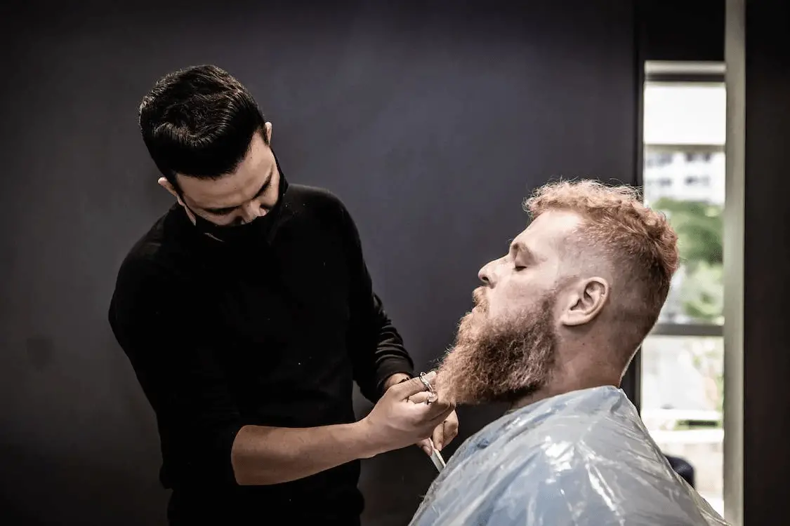 barber trimming a mans long beard with scissors how to trim a beard